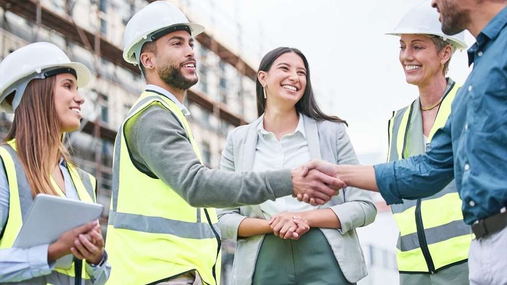 Smiling Workers Shaking Hands at Construction Site